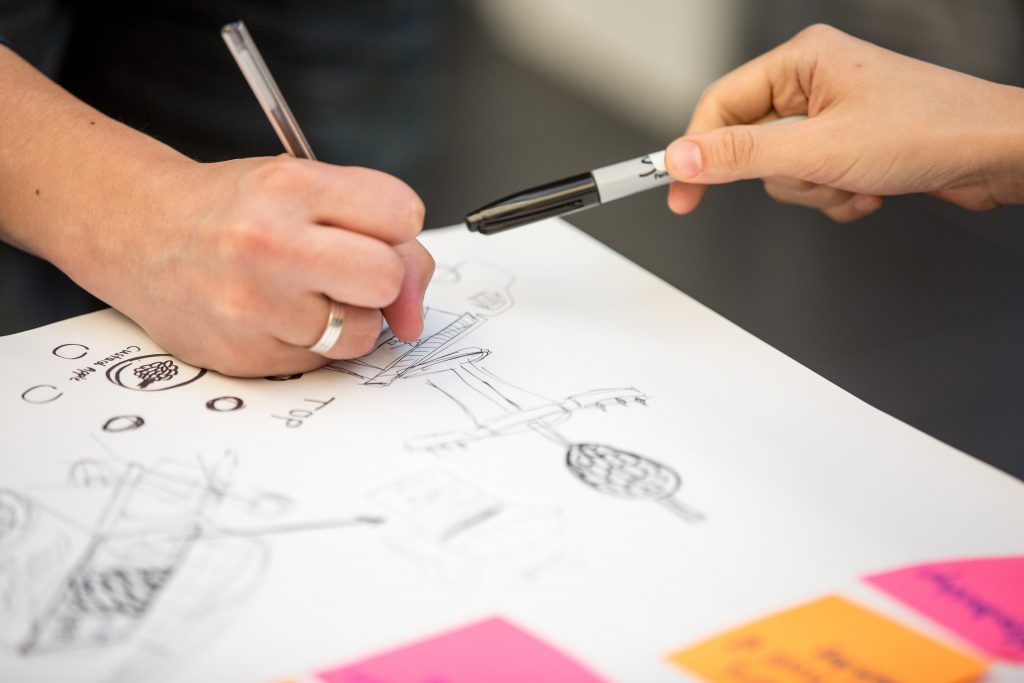 Hände mit Stiften über Papier mit Zeichnungen