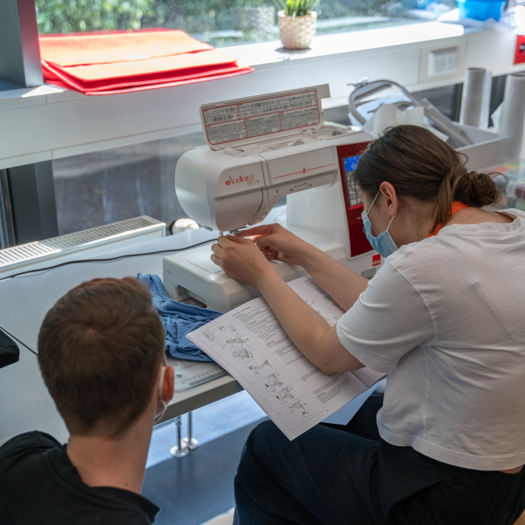 DigiLab-Mitarbeiter erklärt Besucherin Stickmaschine